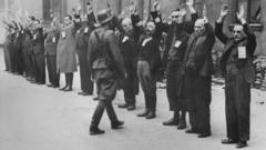Um soldado da SS, a milícia nazista, aborda trabalhadores judeus no gueto de Varsóvia em 1943
