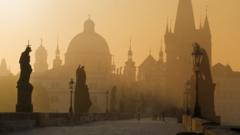 Prague's famous Charles Bridge is seen in an early morning mist, lending the scene a mysterious ambience