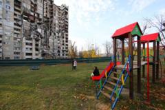 Niños ucranianos en un parque frente a un edificio derruido