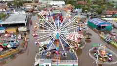 Aerial view of a flooded amusement park including a large ferris wheel.