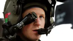 Prince Harry in 2012 wearing a green helmet attached to an eyepiece that is over one eye and a mouthpiece in front of his mouth