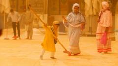 A boy sweeps sand.