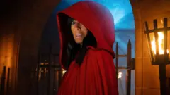 Claudia Winkleman wearing the red cloak on The Traitors