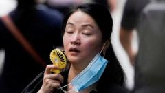 A woman uses a handheld fan while walking along the street in Shanghai