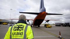 A Dfid employee wearing a UK aid hi-vis heads towards a plane