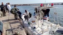 A Tunisian national coast guard helps a child to get off a rescue boat