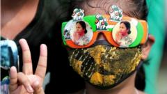 A Trinamool Congress party (TMC) supporter wears glasses with pictures of party supreemo Mamata Bannerjee and shows victory sign as they celebrate after winning an absolute majority in the West Bengal Assembly Election in Kolkata, India, 02 May 2021