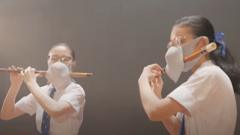 Two schoolgirls in Hong Kong wearing masks while playing the flute