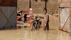 A boy stands with his bicycle in knee-deep muddy water in Nowshera