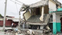 People drive in a motorcycle past a damaged home in Les Cayes, Haiti, on 17 August 2021