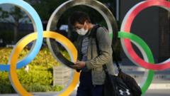 A passerby walks past an Olympic Rings monument displayed near the National Stadium, the main venue of the Tokyo 2020 Olympics and Paralympics, in Tokyo, Japan,