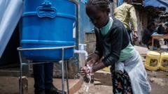 肯尼亚首都奈罗毕一处平民窟内一名小孩在慈善组织布置的临时水缸学习正确洗手防疫方法（18/3/2020）