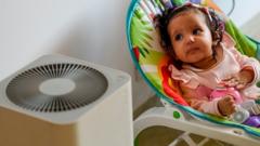 A baby rests near an air purifier at her residence in New Delhi.