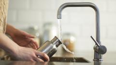 A woman cleans a water bottle in a kitchen sink