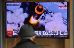 People watch a television screen showing a news broadcast with file footage of a North Korean missile test, at a railway station in Seoul on March 16, 2022