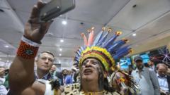 A man in indigenous clothing takes a selfie with a phone.