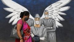 A woman wearing a face mask walks past a graffiti painted to create awareness about the coronavirus disease. Graffiti, besides creating awareness about coronavirus pandemic, it is painted to beautify the walls in Vashi (a suburb in Navi Mumbai).