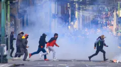 A handful of protestors run across the road with smoke rising in the background