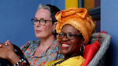 Mpho Tutu van Furth laughs as she sit back on one chair with her wife Marceline for di background.