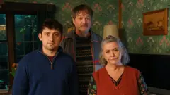 A still from the series showing Craig Roberts, Mark Heap and Dawn French posing as their characters in their dining room.