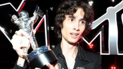 Getty Images A silver astronaut holds up the MTV VMA Moon Man trophy at the sombre 2025 MTV Video Music Awards.