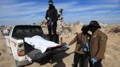 Israel says Palestinian groups returned body of Thai hostage 9 Reuters Hamas and Palestinian Islamic Jihad fighters stand next to a body bag that they say contains the remains of one of the last two dead hostages, in Beit Lahia, northern Gaza (3 December 2025)