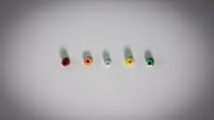 Kevin Church/BBC News Five small round beads arranged horizontally on a white surface. Each bead has a hole in the centre. They are multicoloured, from left to right, they are dark red, orange, light blue, yellow and green.