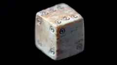 Tony Jolliffe BBC A medieval cubic die made from bone and survives in good condition, with all six faces clearly visible.
