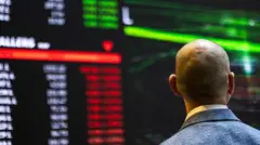 A stock marker trader looks at a large screen