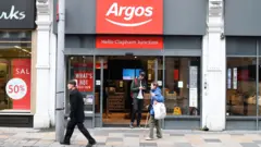 An Argos storefront in Clapham Junction. A young man is walking out of the shop while two people walk past it.