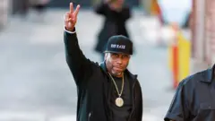 Rob Base photographed on the streets of New York throwing up the peace sign