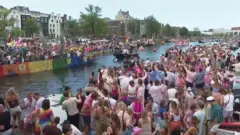 Revellers line Amsterdam canal to watch the annual Pride boat parade