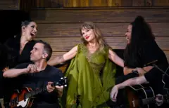 Getty Images Taylor Swift holds hands with her backing singers during a performance on her Eras tour