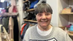 Photograph of Mandy Carter from Reddish. She is pictured wearing a jumper inside a charity shop in the Reddish area of Stockport.