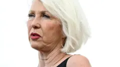 close-up of Peters, who has short white hair and is wearing red lipstick