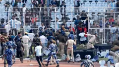Reuters Crowds storm fences surrounding a football pitch in India.