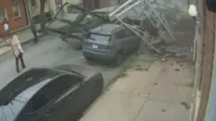 Debris from a collapsed building lies in the road and on top of a car.