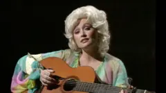 A young Dolly Parton playing an acoustic guitar