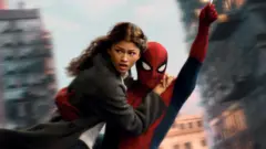 Spider-Man swings through the city on web whilst holding MJ, played by Zendaya.