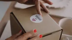 Woman attaches label to cardboard box
