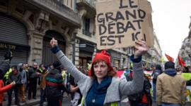 A Yellow Vest protester in Toulouse with a phrygian cap holds a placard reading 'The big debate is here' - 26 Jan 2019