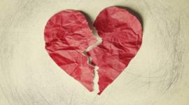 A crumpled paper heart, torn in half