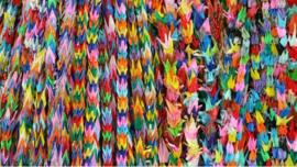 multi-coloured origami paper cranes hanging in vertical rows