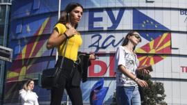 People walk in front of the offices of the European Union with logos reading "EU for You", in Skopje, North Macedonia (18 Oct 2019)