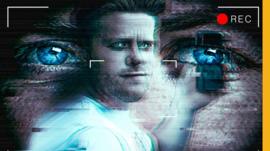 Connor holding a phone in front of a pair of eyes in the background