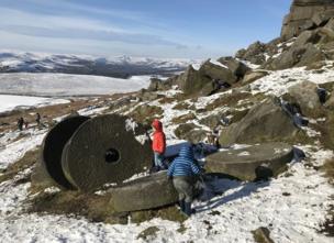 Children playing around stone wheels amongst snow-covered mountains