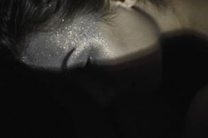 A girl covered in glitter with her face in the shade
