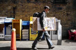 A rough sleeper carries a homemade motivational placard.