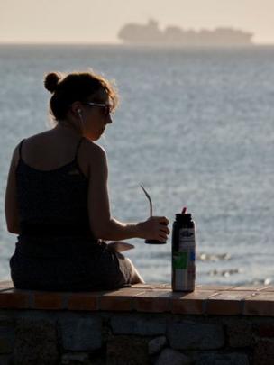 Mujer tomando mate en la rambla de Montevideo.