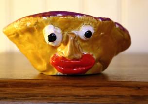 A glazed piece of pottery with a funny face on it
